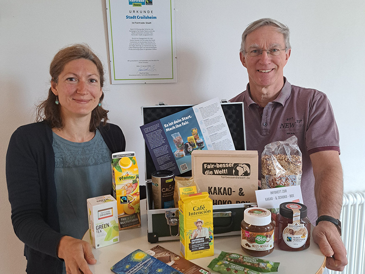 Eine Frau und ein Mann stehen an einem Stehtisch mit Fairtrade-Produkten